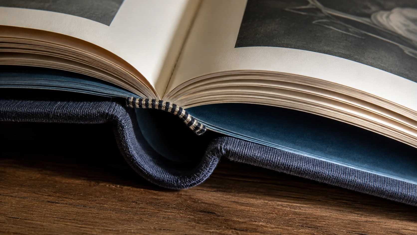Раскрытая книга в твёрдом переплёте с круглёным корешком и капталом